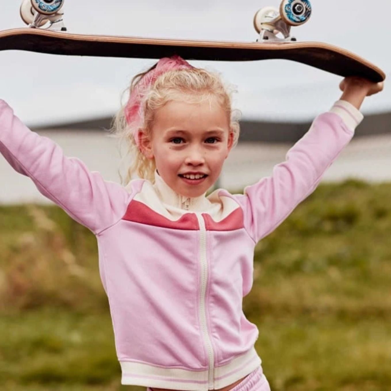 Petite fille qui tient un skateboard dans ses deux mains