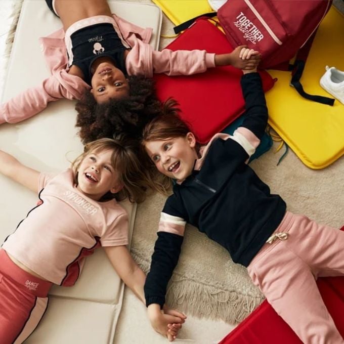 Trois enfants allongés sur le sol.