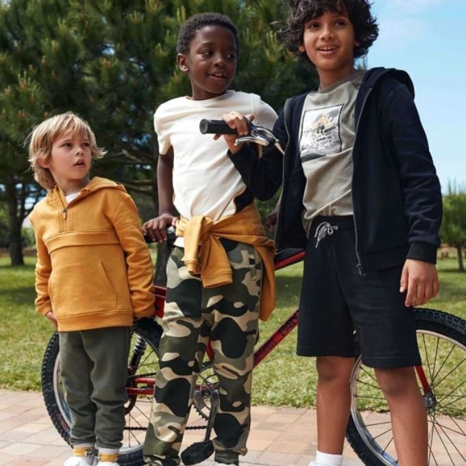 Trois petits garçons debout devant un vélo 