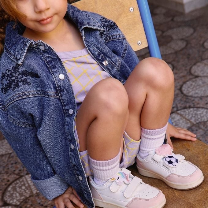 Petite fille assise sur une chaise portant des basket rose blanche
